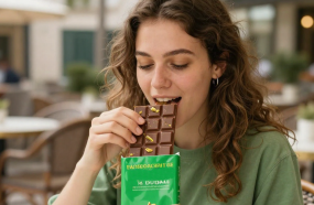 une jeune femme déguste une tablette de chocolat fourrée à la pâte de pistache à la terrasse d'un café